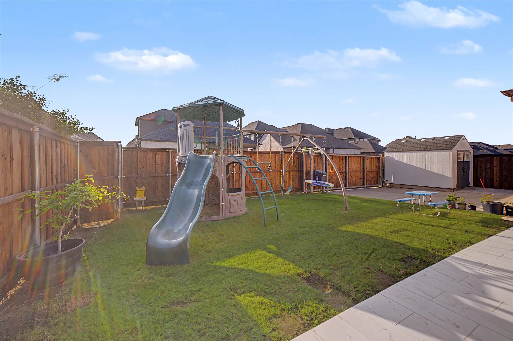 Expansive backyard featuring a lush lawn, privacy fencing, and a hardscaped patio