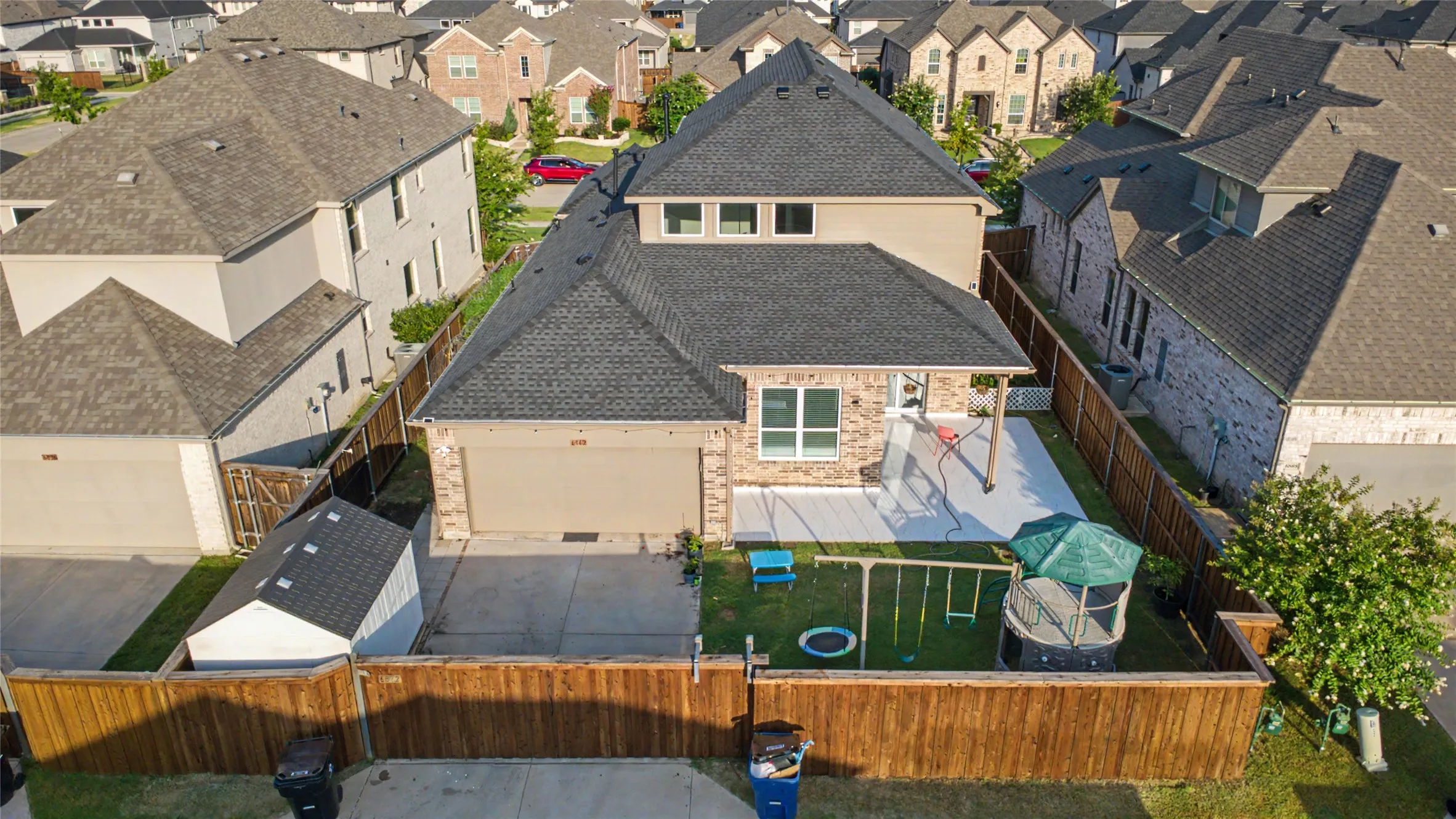 Rear exterior featuring a covered patio, fenced yard with grass, and a detached storage shed