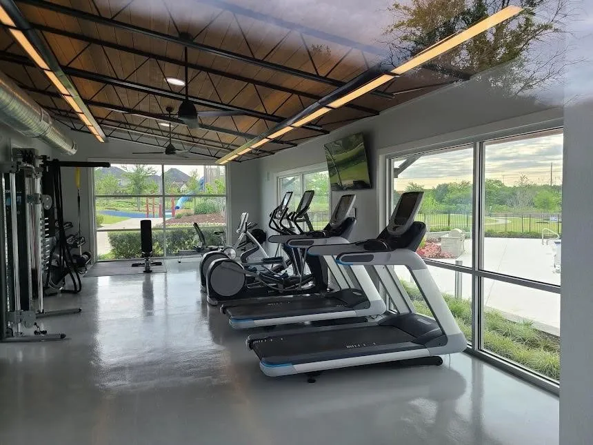 Fitness center featuring a vaulted ceiling with exposed beams, recessed lighting, and expansive windows