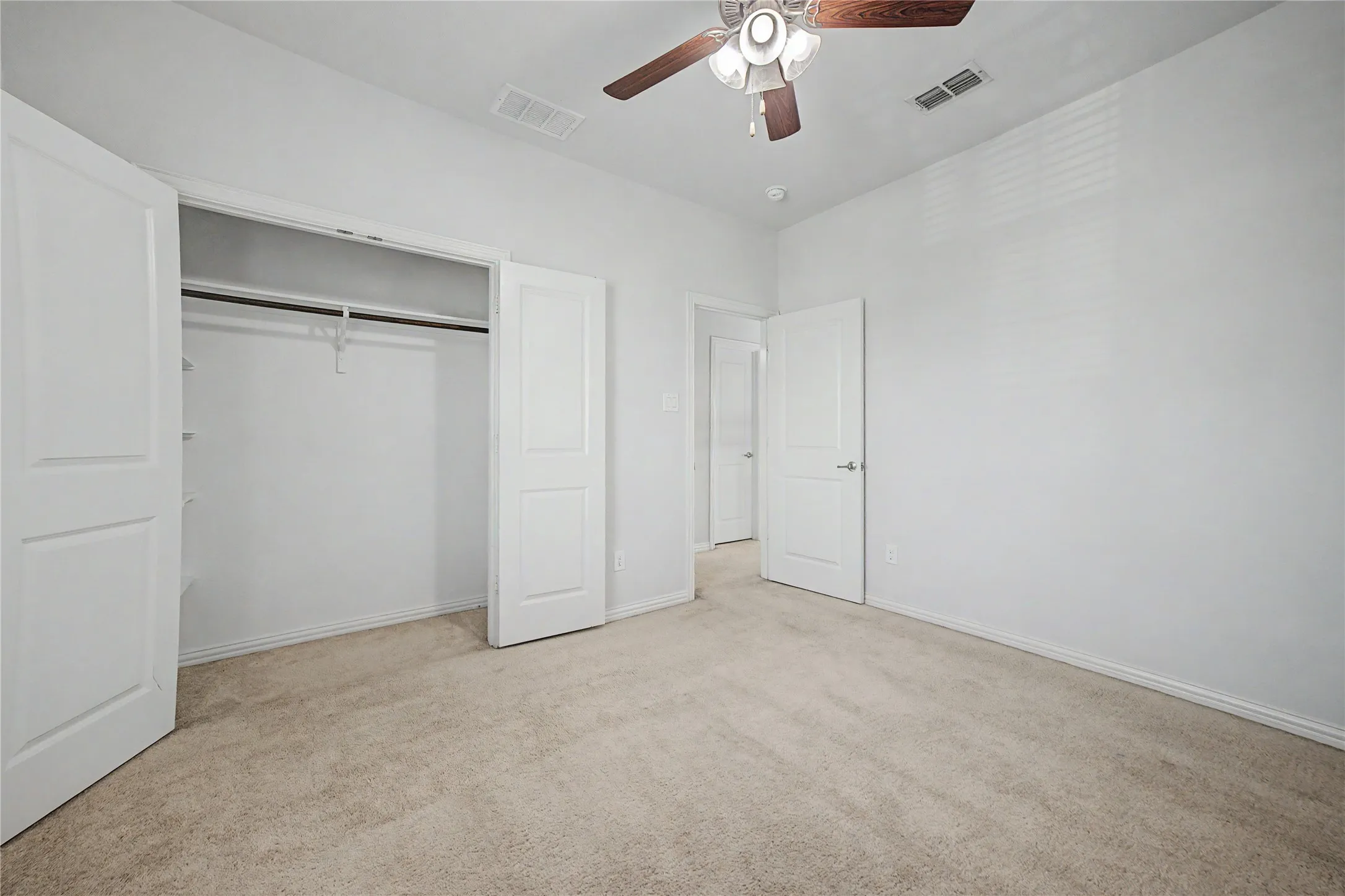 Recessed ceiling lighting, ceiling fan with wood-finish blades, light-toned carpet flooring, white walls, and white bi-fold closet doors
