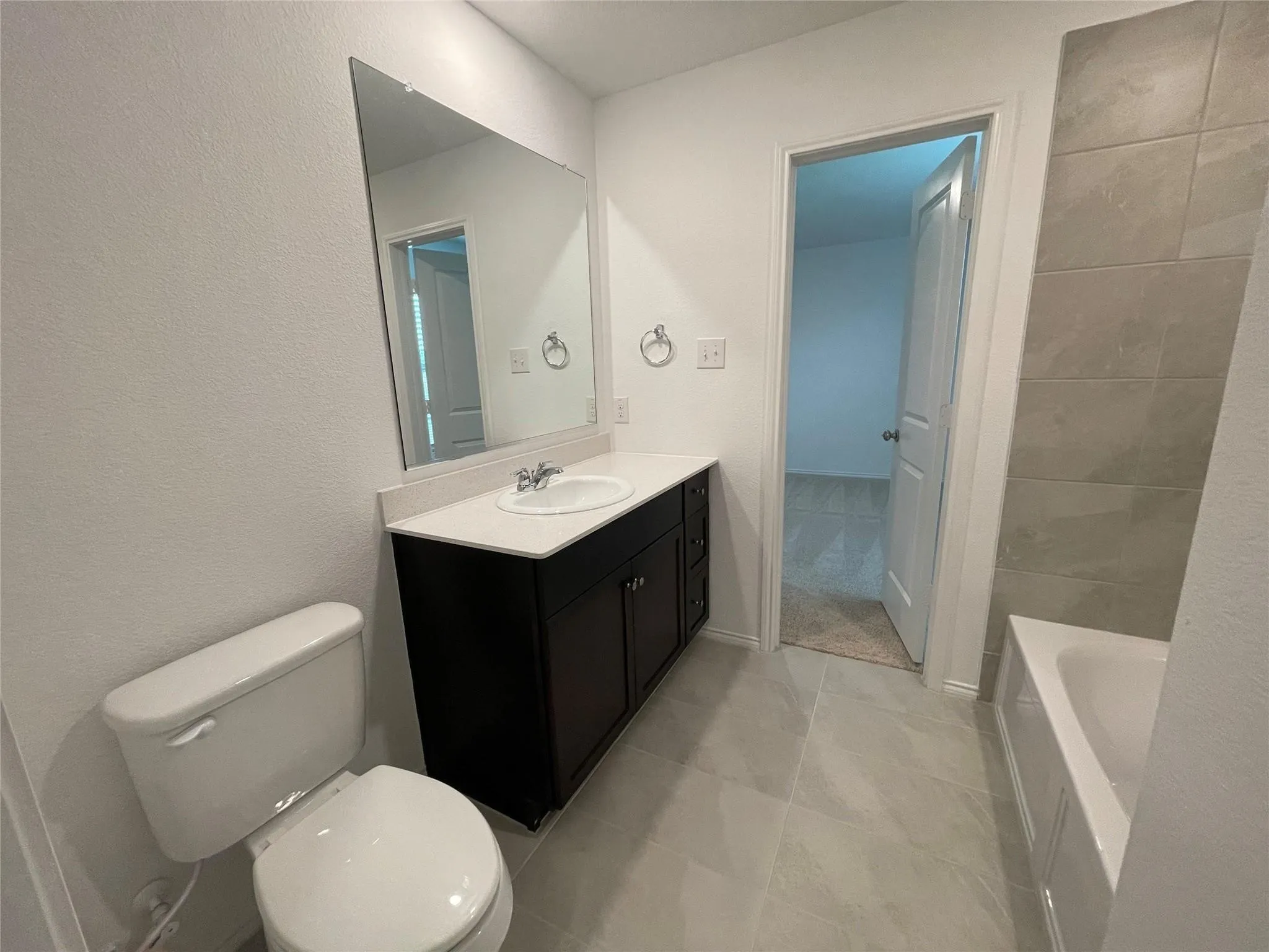 Bathroom featuring a dark wood finish vanity with a white countertop, a built-in rectangular sink, and tile flooring