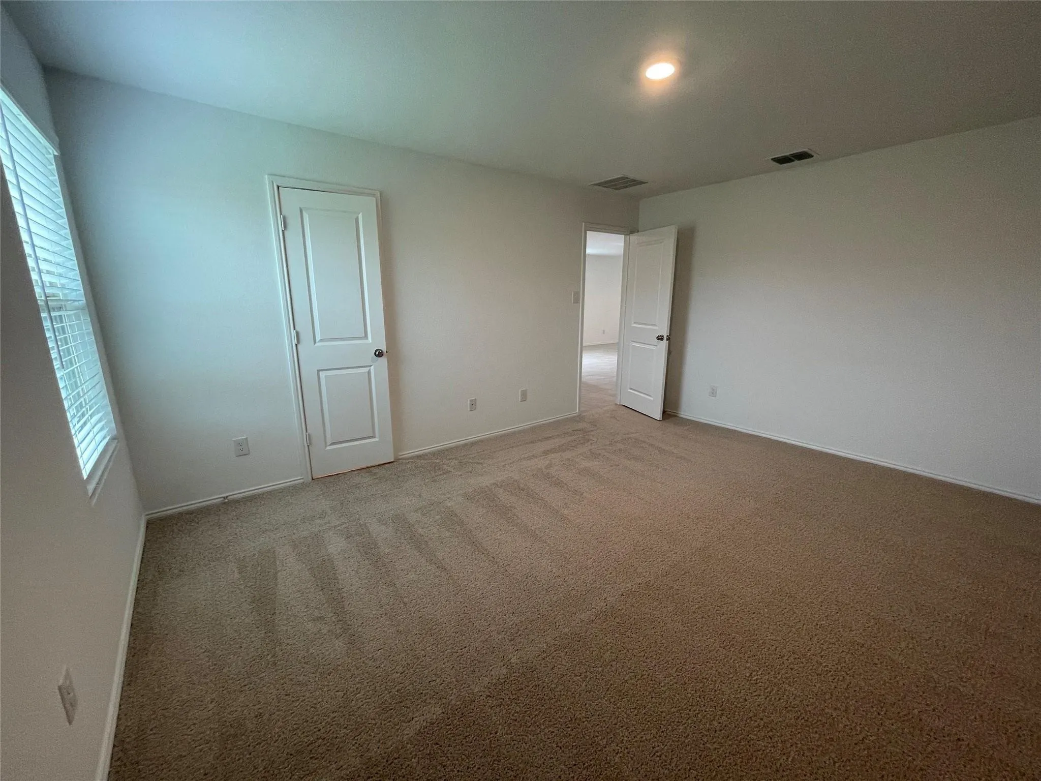 Carpeted flooring, white walls, white paneled doors, recessed lighting, and a window with blinds