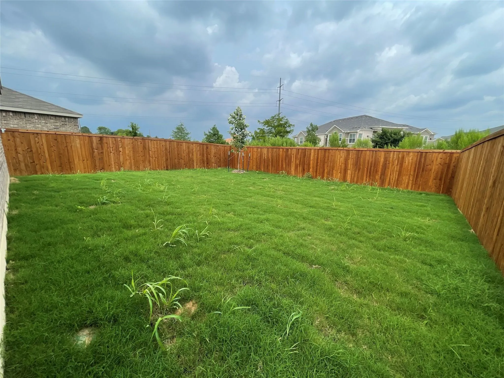 Expansive rear yard featuring natural wood privacy fencing and a grass lawn