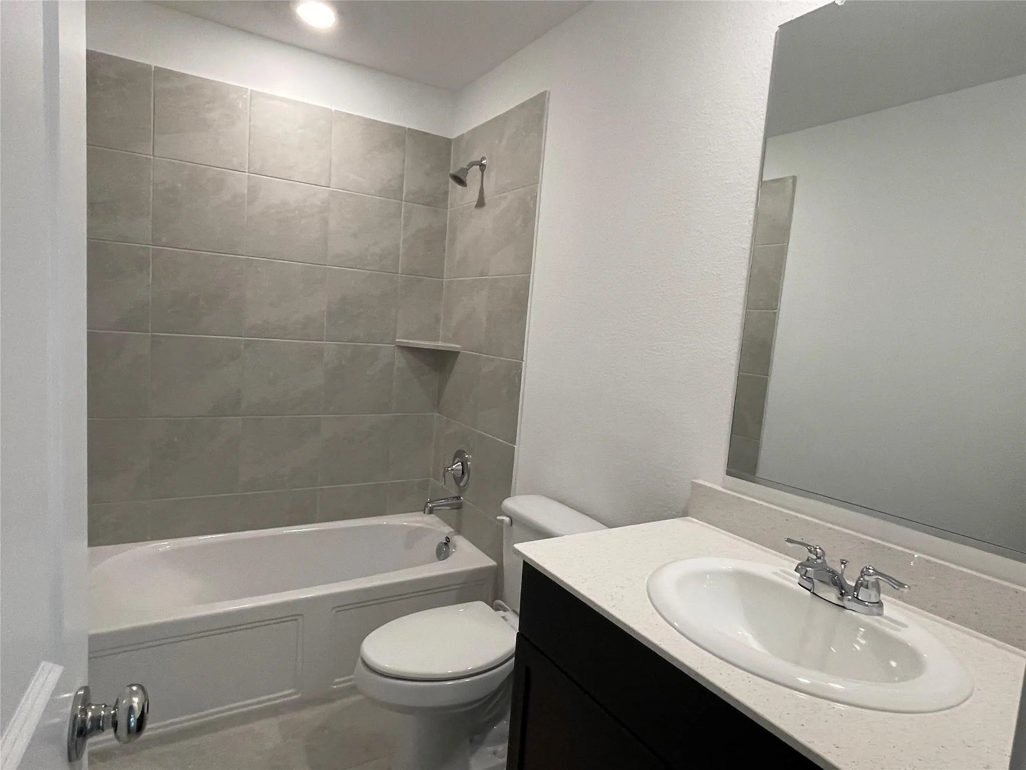 Full bathroom featuring a single vanity with stone-finish countertop, undermount sink, and chrome fixtures