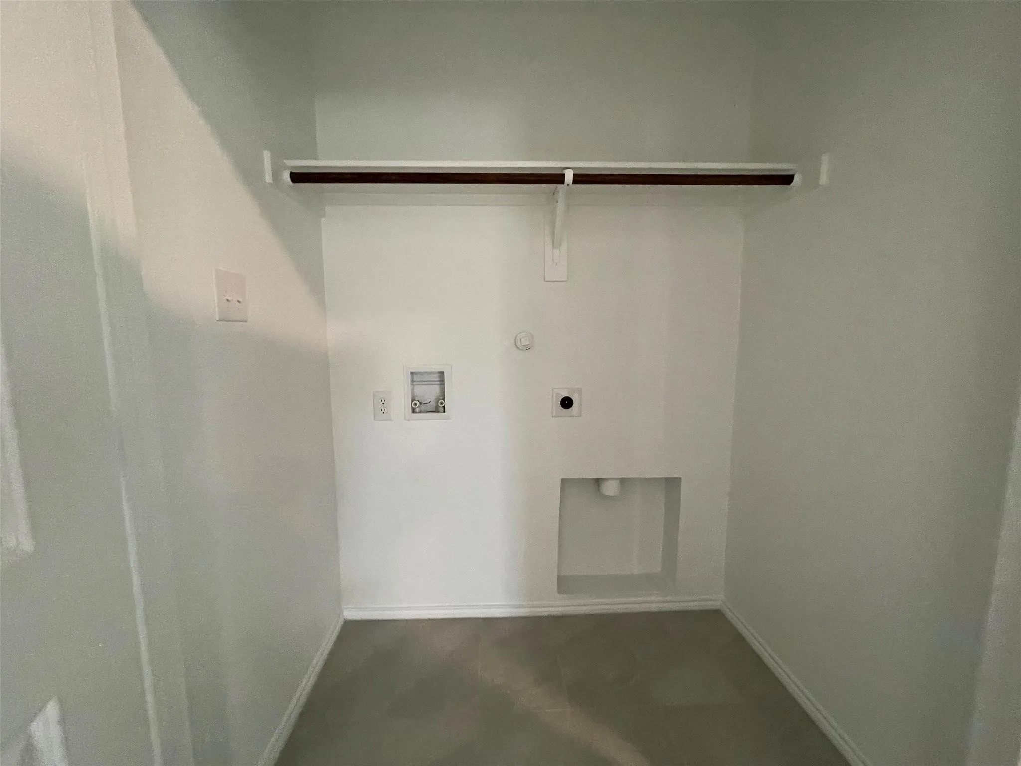 Laundry area with a built-in shelf, hanging rod, and utility connections