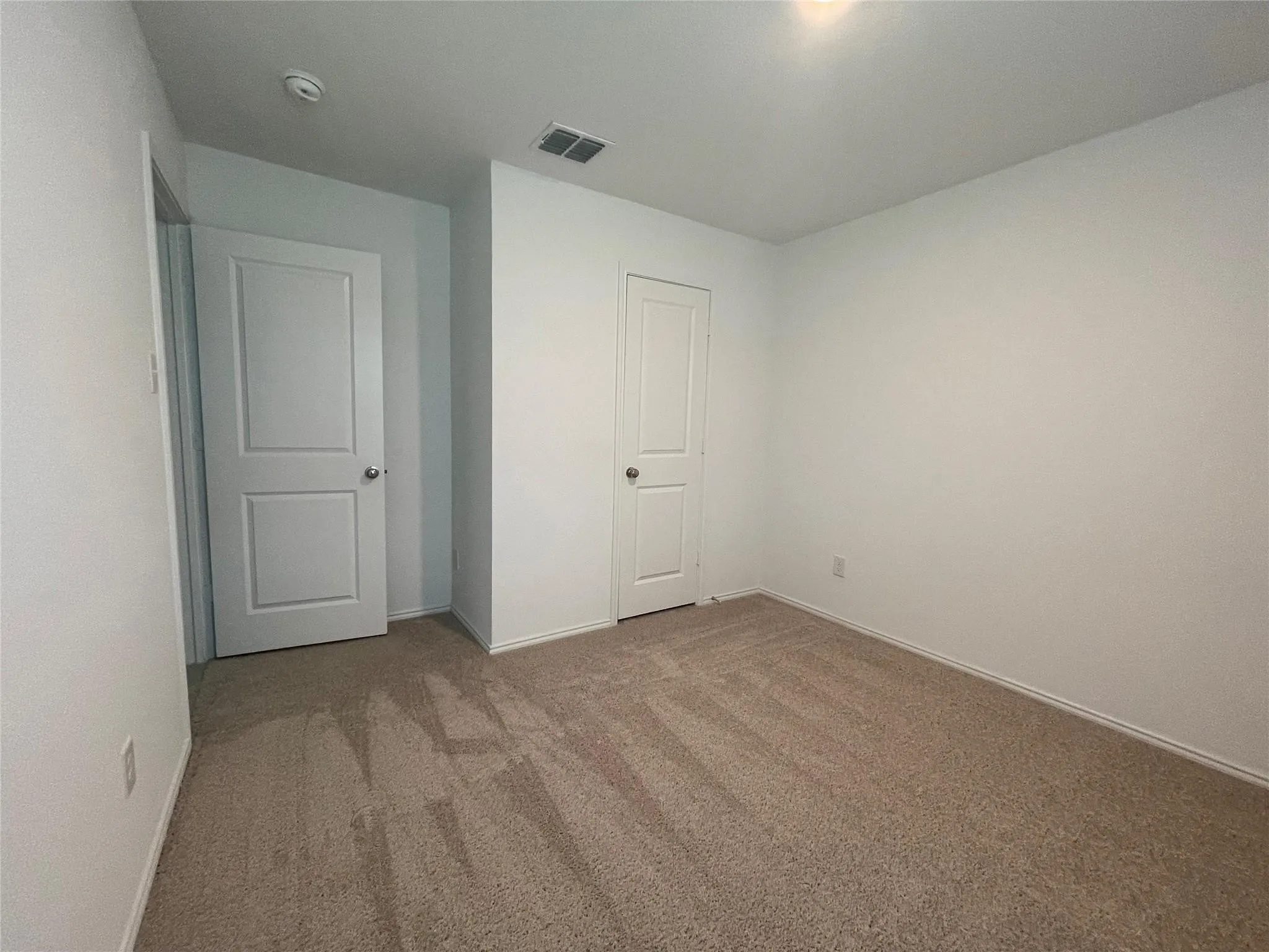 Neutral wall color, light tan carpeting, and recessed ceiling lighting
