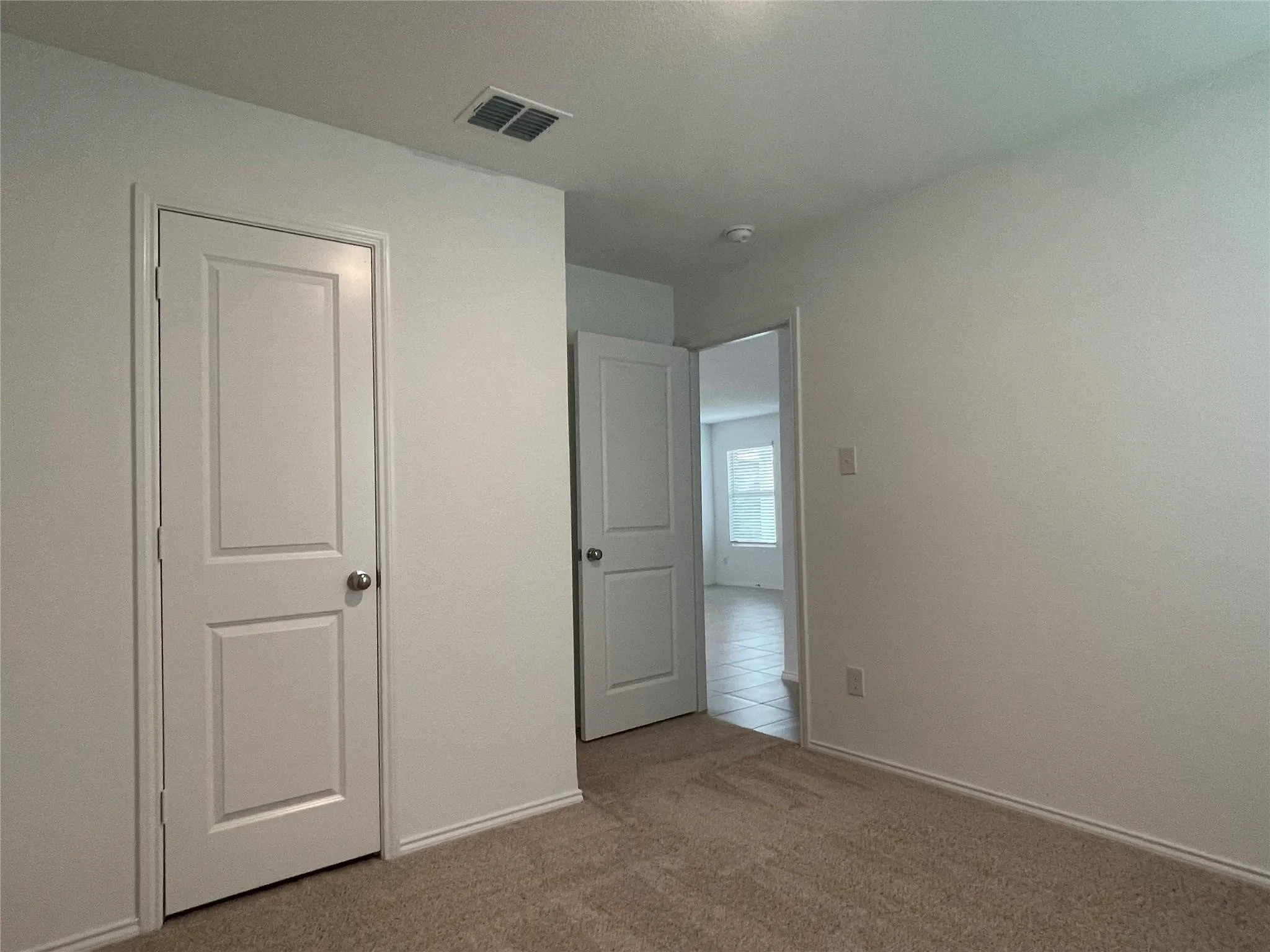 Neutral wall paint, carpeting, two-panel interior doors, and a ceiling-mounted smoke detector