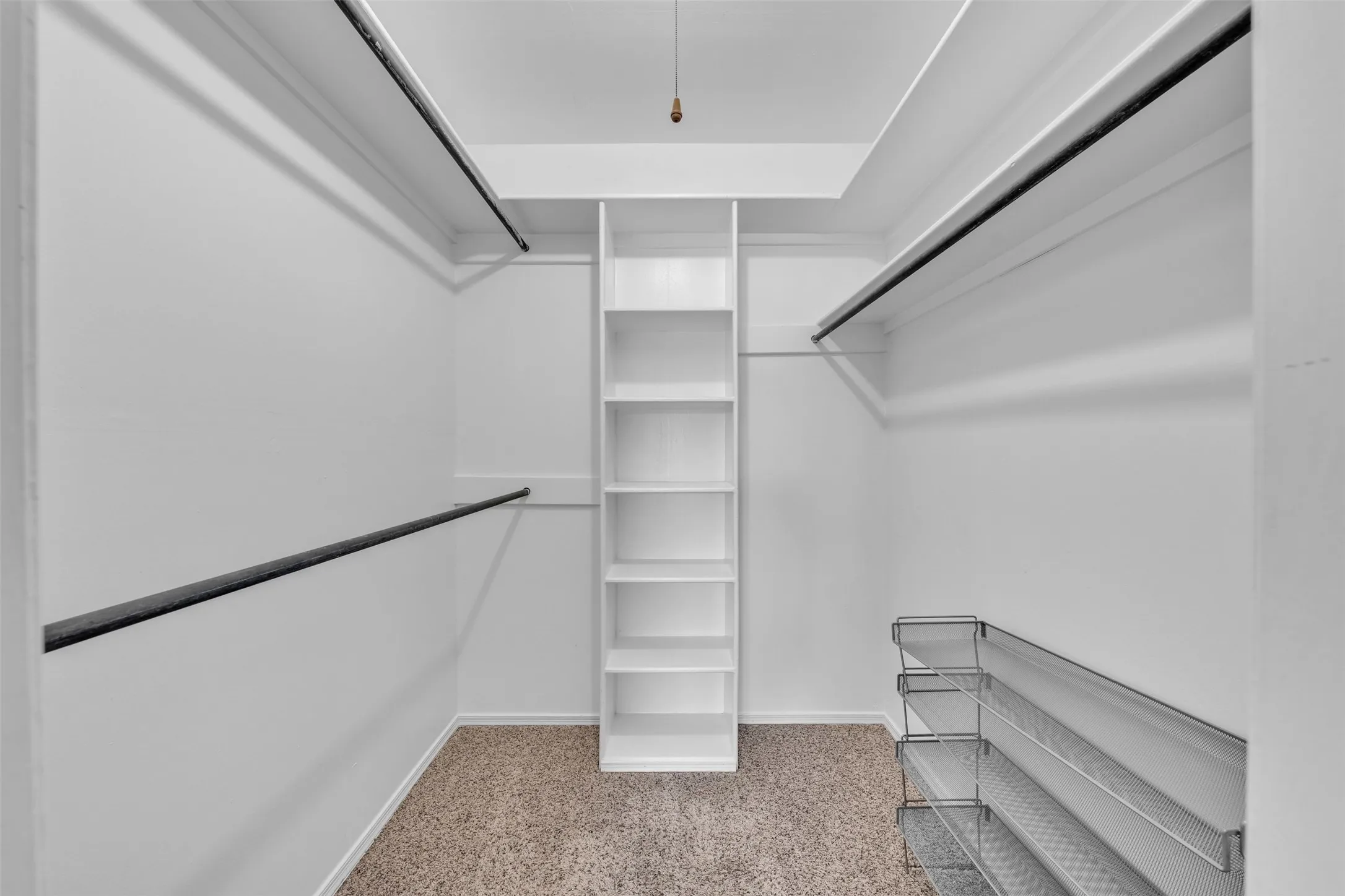 Spacious closet with white walls, built-in shelving, two levels of hanging rods, and carpet flooring