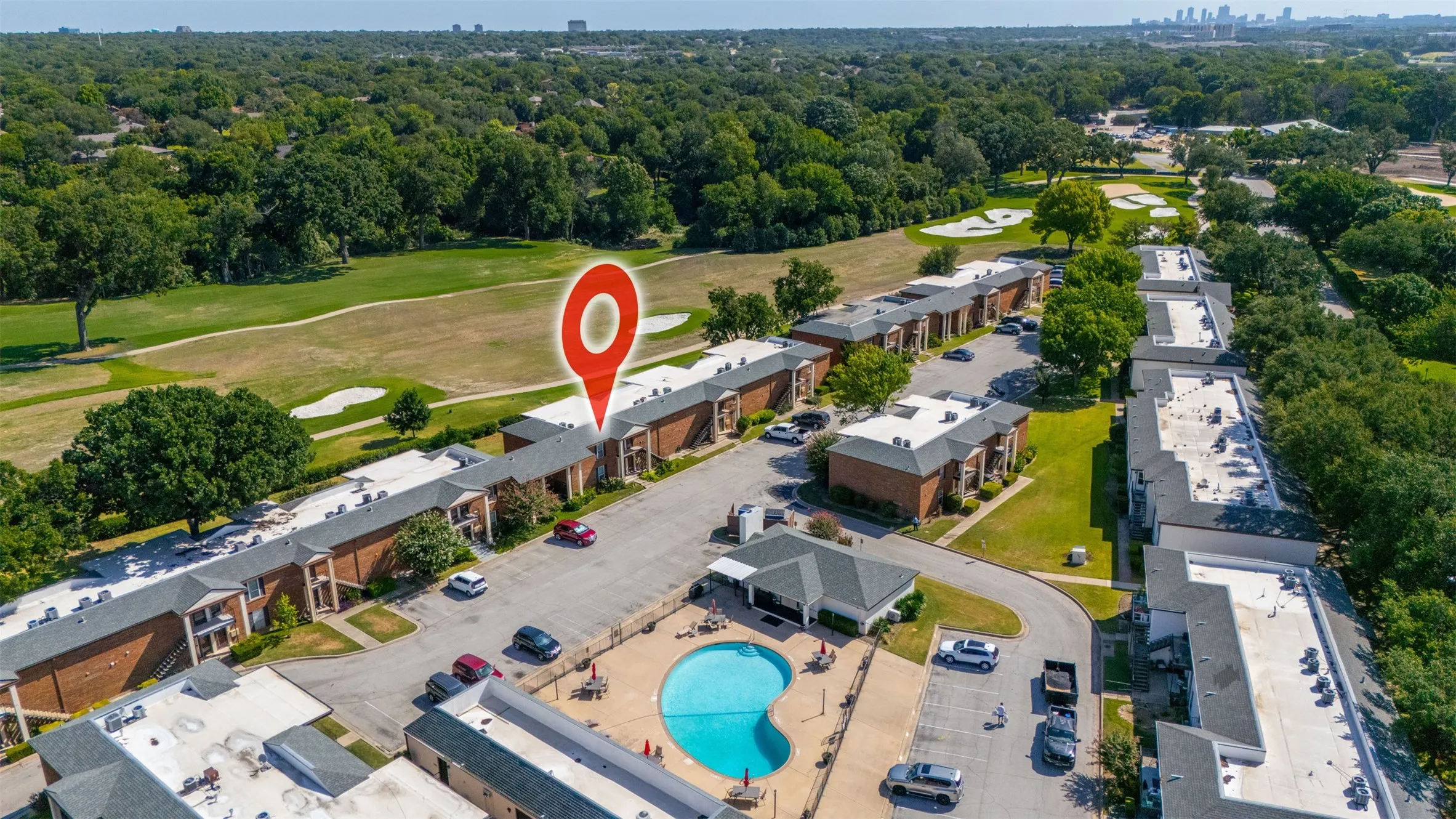 Community buildings featuring a swimming pool, adjacent paved parking, and lush green spaces
