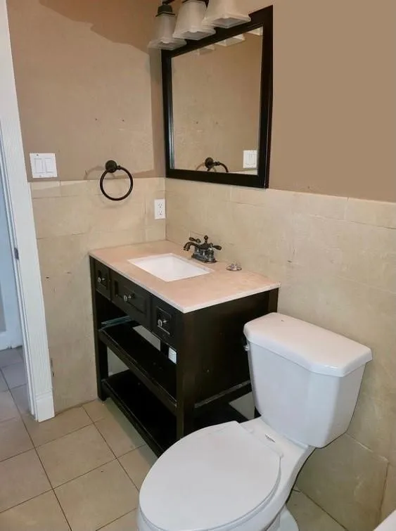 Bathroom featuring a dark wood vanity with a light-toned countertop, a white basin, and a wall-mounted mirror