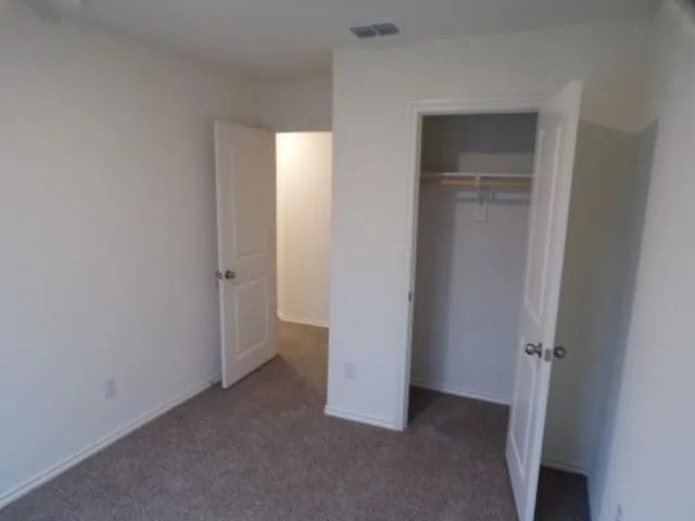 Carpeted flooring, white interior doors, built-in closet rod, and white wall finishes