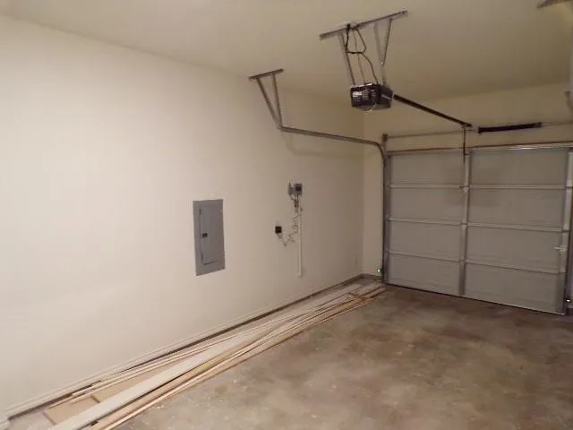 Spacious garage featuring a concrete floor, overhead door, and wall-mounted electrical panel