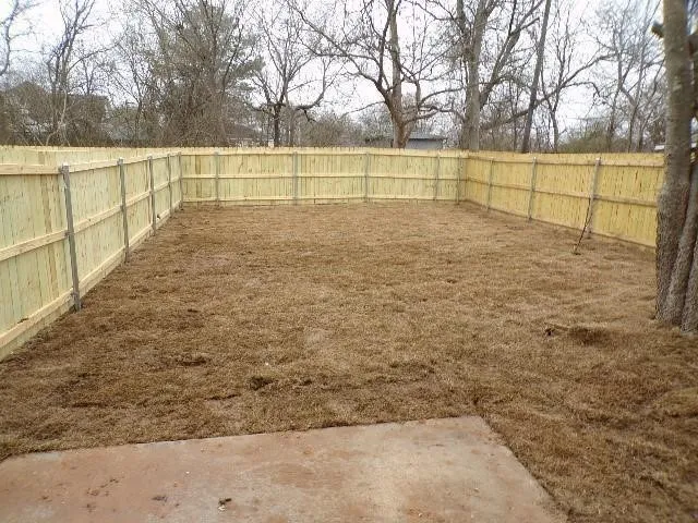Expansive backyard featuring a new wood privacy fence and a concrete patio