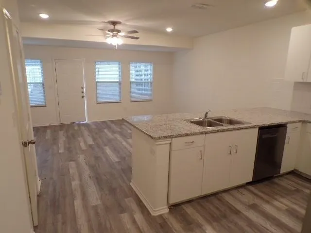 Kitchen island with a double basin sink, light-toned countertops, and white cabinetry