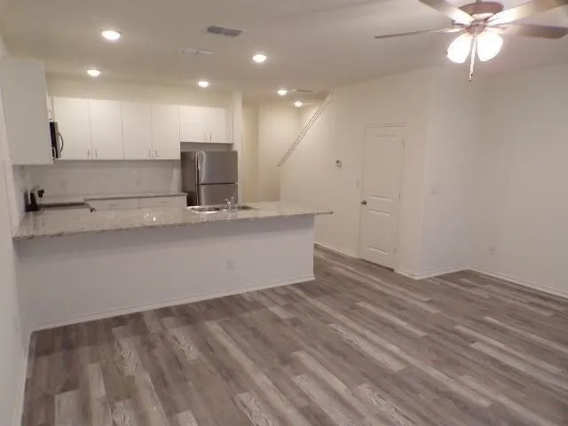 Kitchen featuring white cabinetry, granite countertops, stainless steel appliances, and a breakfast bar with a stainless steel sink