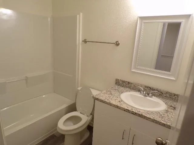 White vanity with granite-finish countertop, under-mount sink, framed mirror, and chrome fixtures