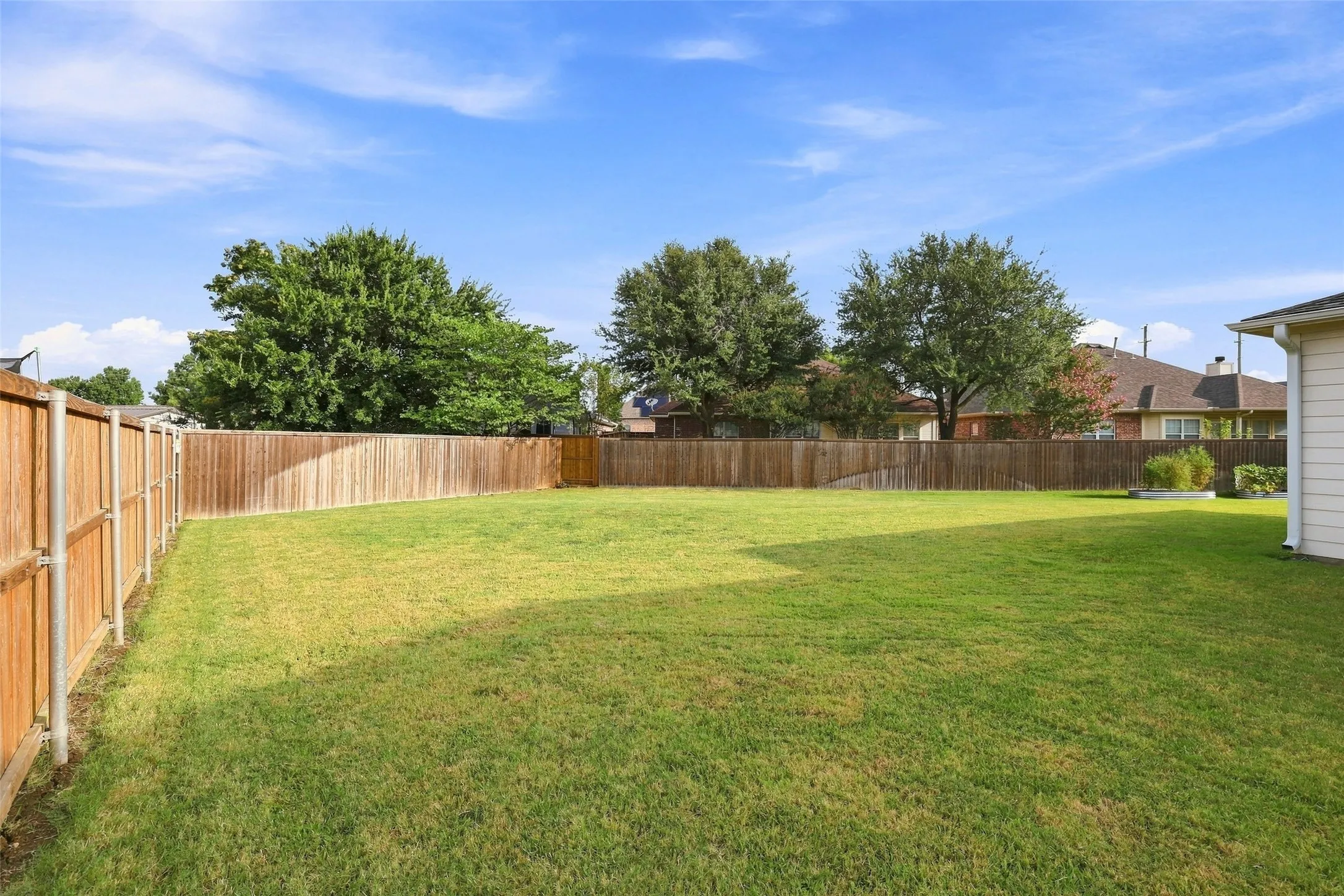 Expansive lawn area enclosed by a wood privacy fence