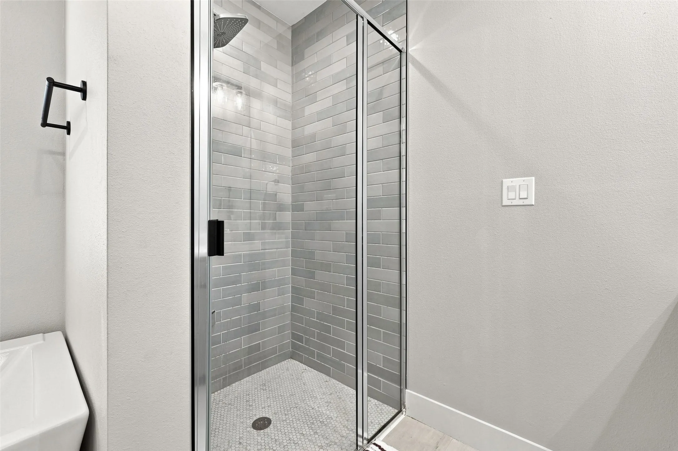 Glass-enclosed shower featuring subway tile surround, rain shower head, and mosaic tile flooring