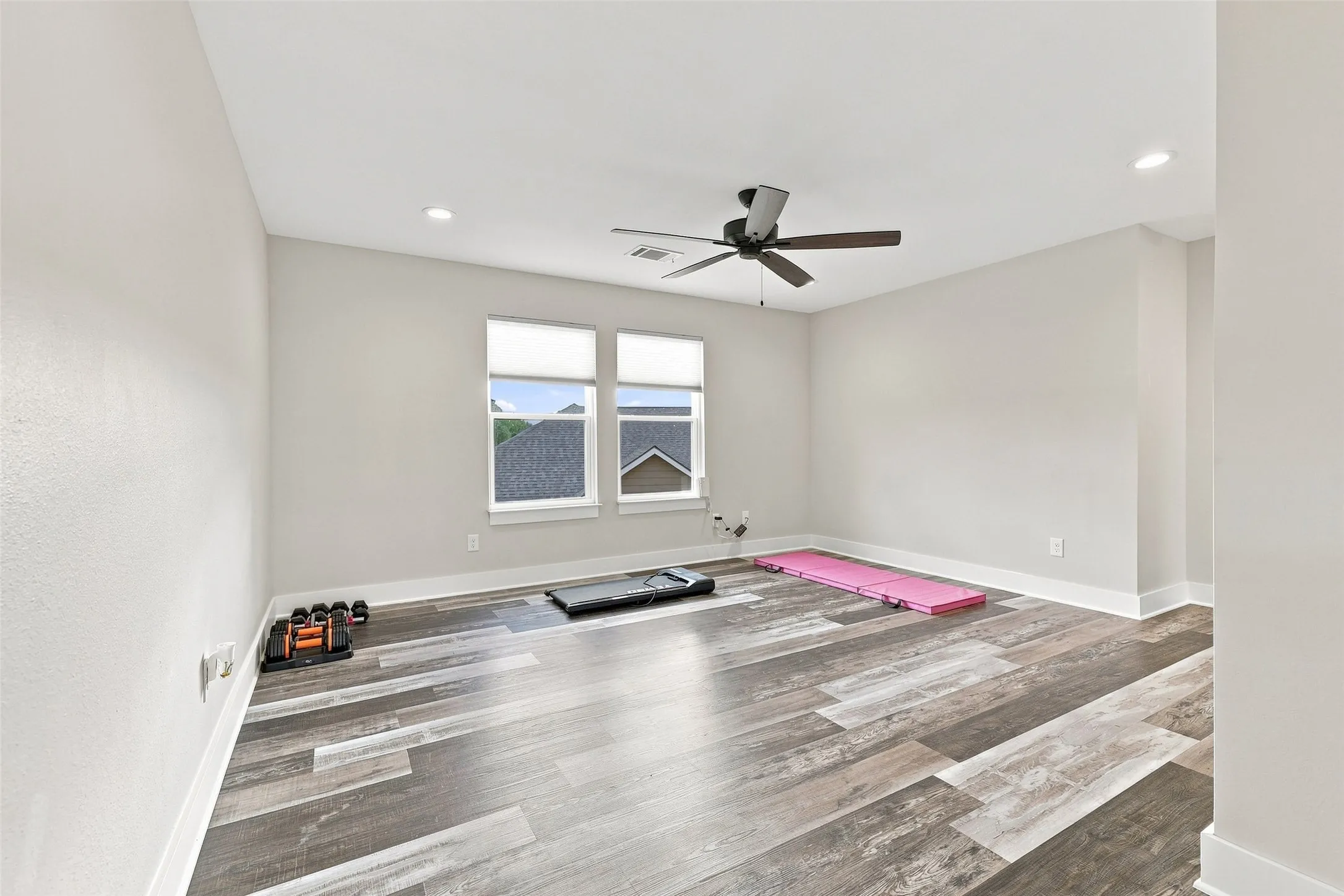 Wood-finish flooring, recessed lighting, ceiling fan, and two windows with blinds