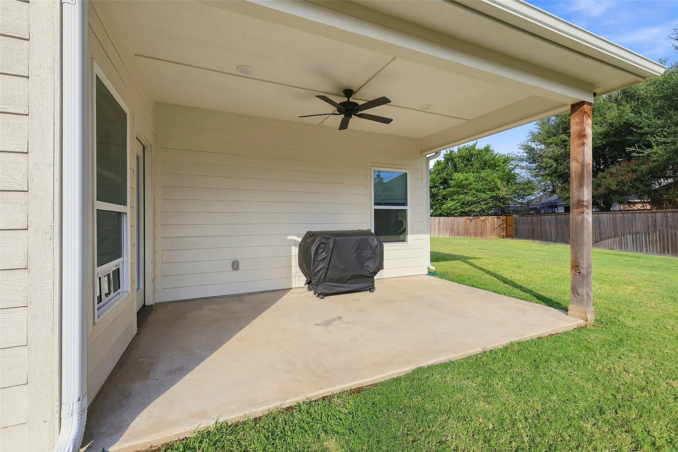 Covered patio with concrete flooring, wood post, and ceiling fan
