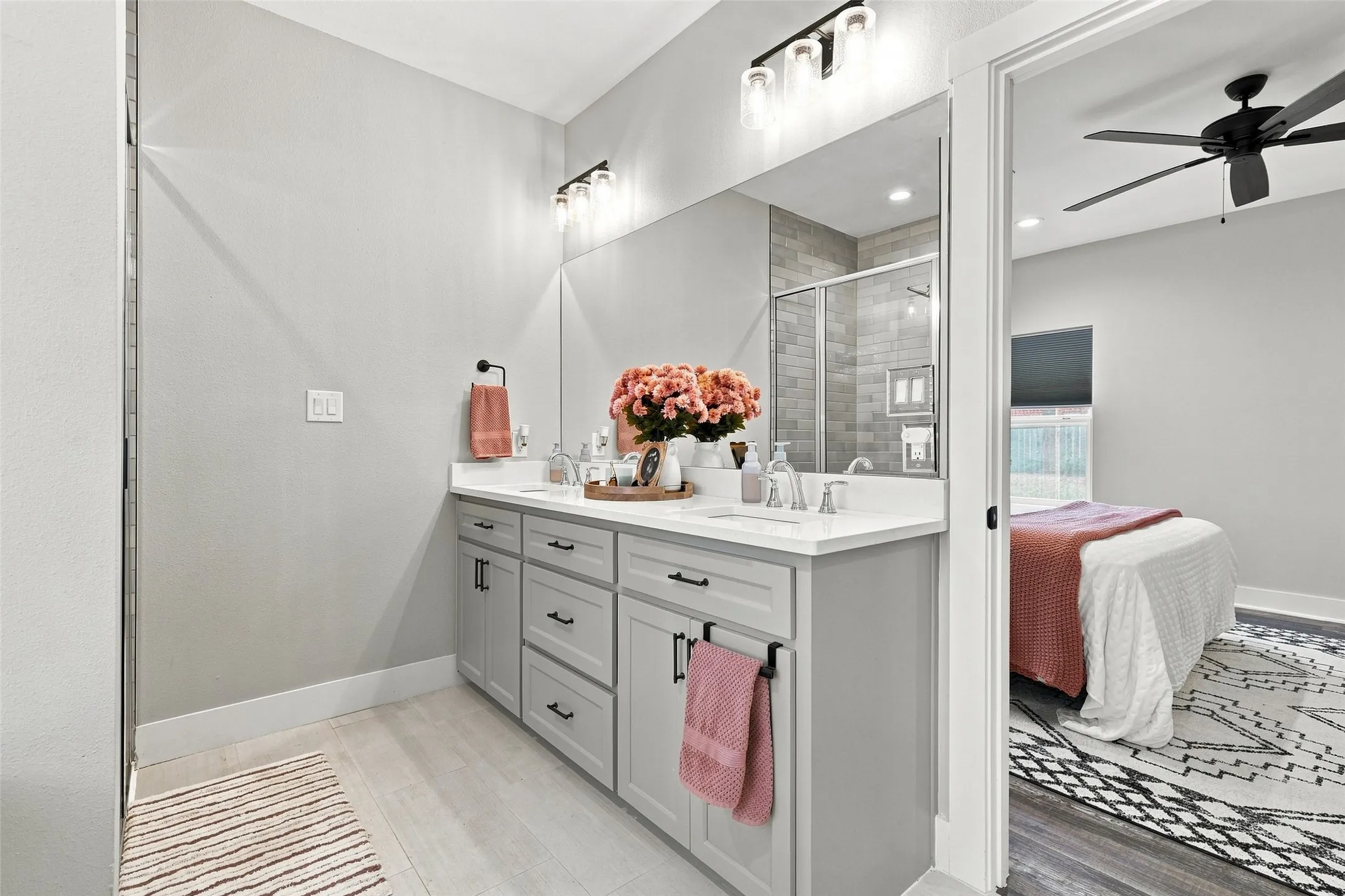Dual vanity with light gray cabinetry, quartz countertops, and matte black hardware