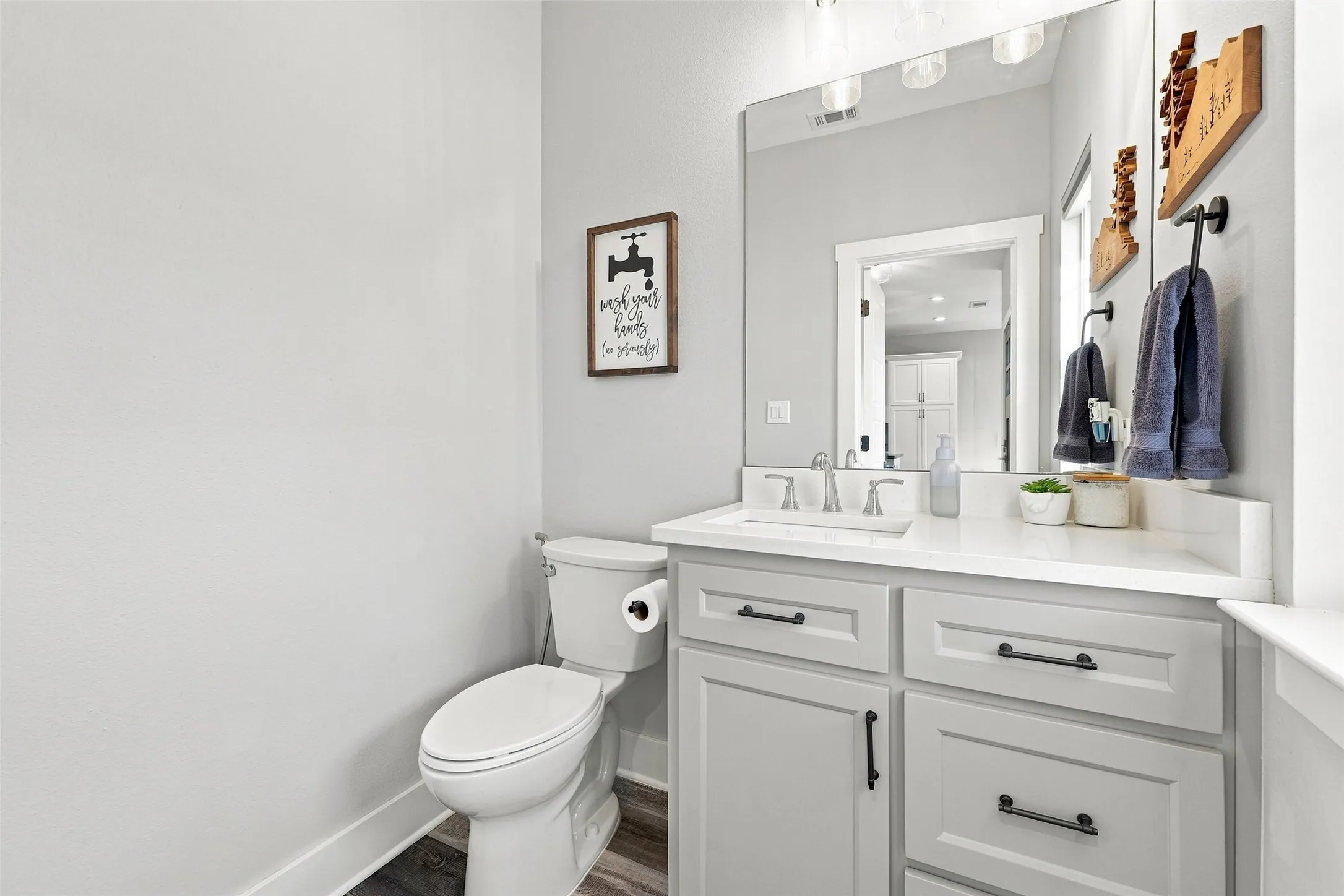 White vanity with inset cabinetry, light-colored countertop, undermount sink, and dark hardware