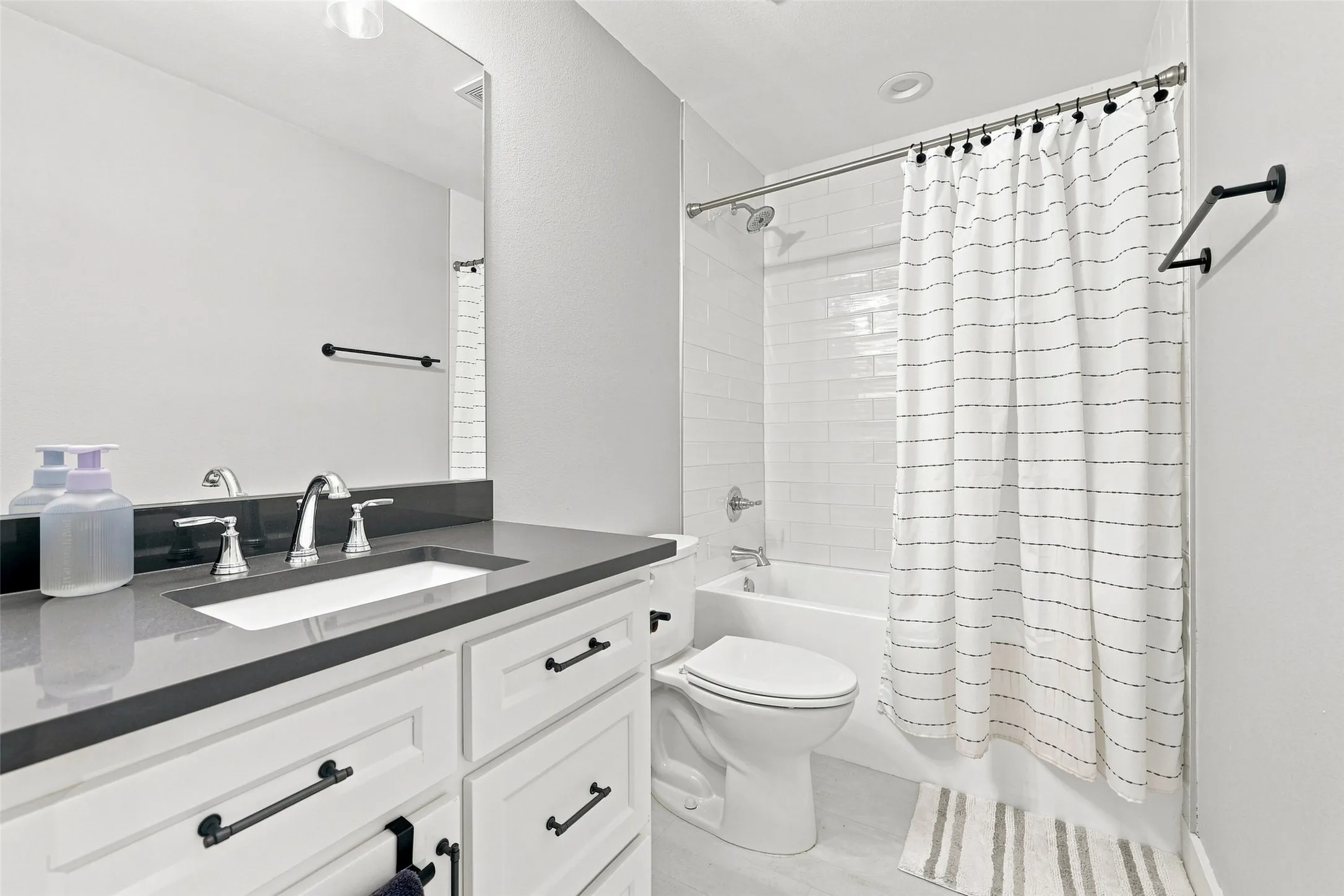 White shaker vanity with dark hardware, undermount sink, and dark countertop