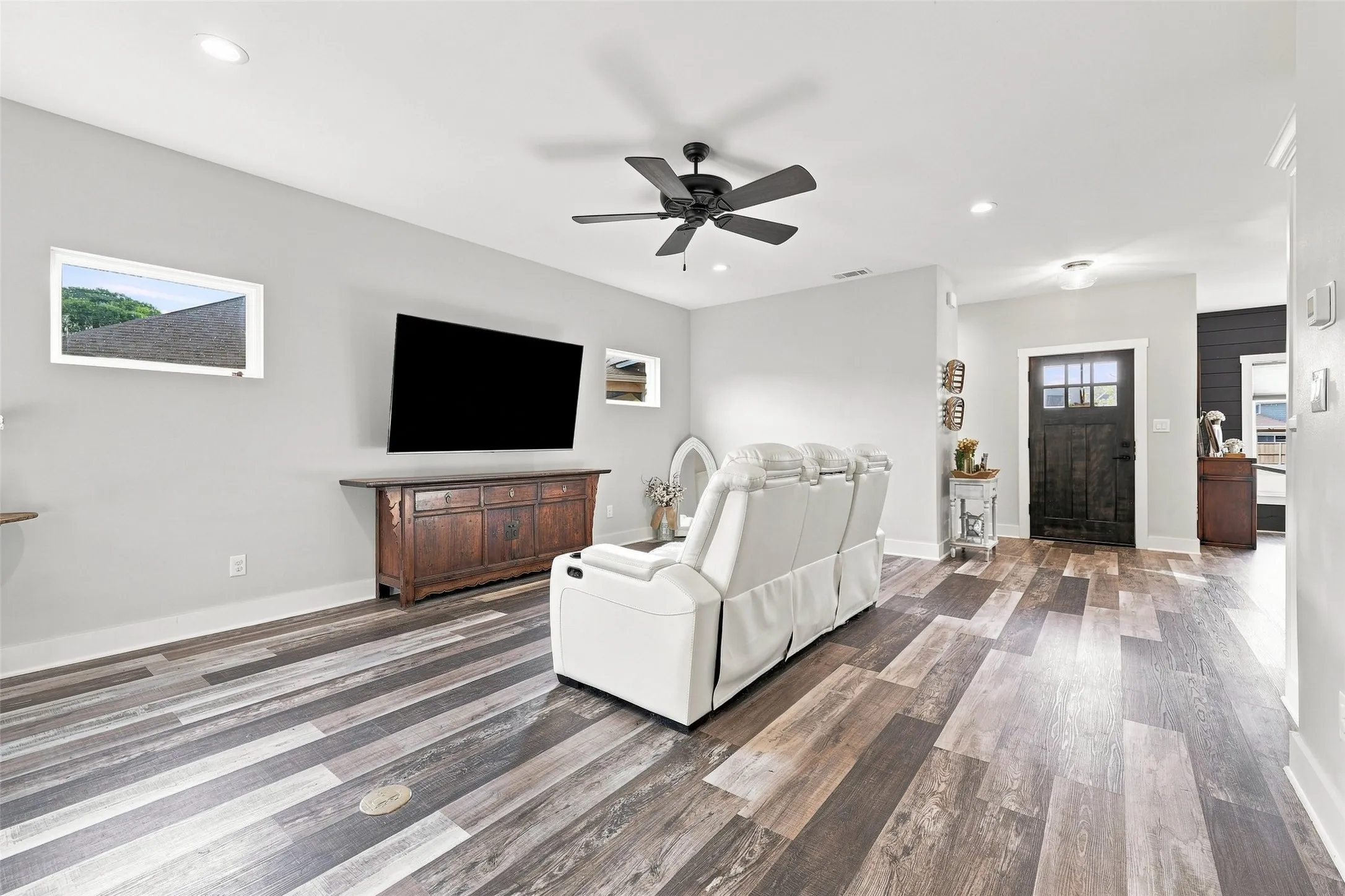 Wood-finish flooring, recessed lighting, and a dark wood entry door with clear glass panels