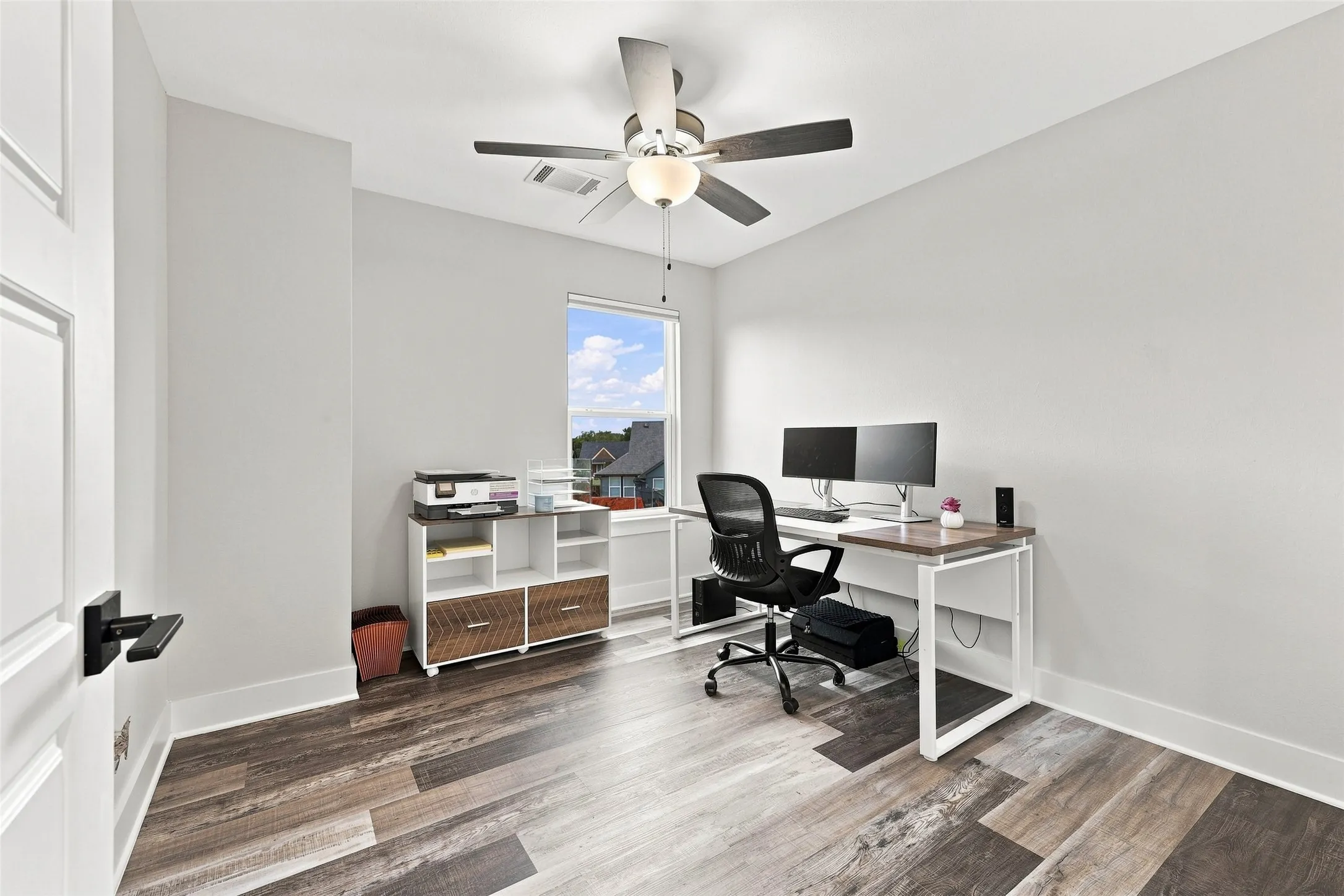 Wood-finish flooring, single window, ceiling fan with light fixture, and contemporary white walls