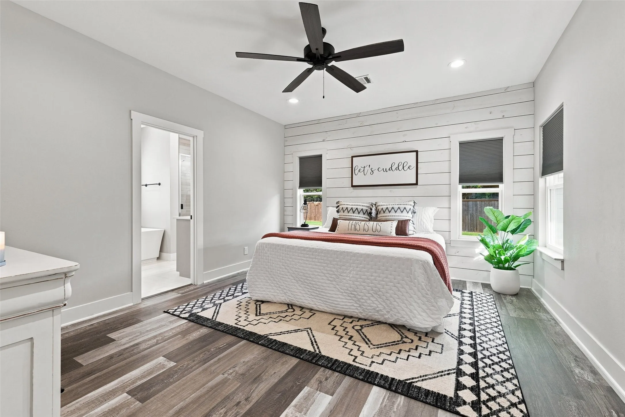 Wood-finish flooring, recessed lighting, ceiling fan, and a white shiplap accent wall with two windows