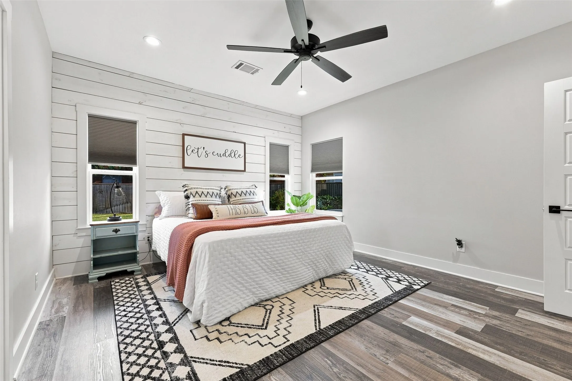 Wood-finish flooring, recessed lighting, ceiling fan, white paneled wall accent, and white interior door with black hardware
