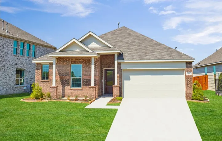 Brick facade home featuring a sloped roofline, attached garage, concrete driveway, and a landscaped front yard with green grass