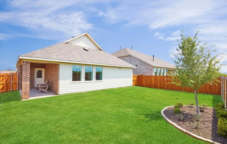 Expansive green lawn with a covered patio featuring brick columns and a concrete surface