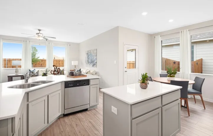 Open-concept kitchen featuring light gray cabinetry, stainless steel appliances, and a double basin sink