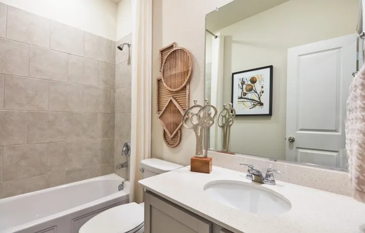 Bathroom featuring a white tub with ceramic tile surround, a built-in vanity with a white countertop, an undermount sink, and chrome fixtures