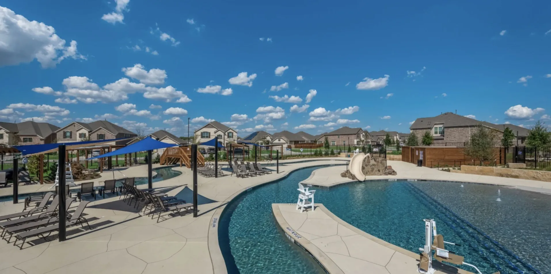 Expansive pool area featuring a lazy river, water slide, and multiple shaded seating areas