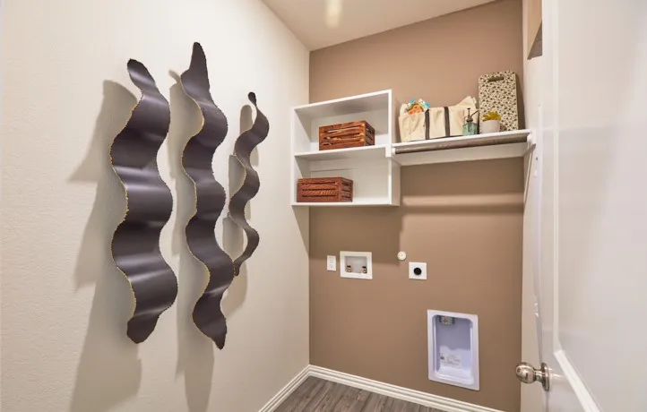 Dedicated laundry space featuring white shelving, a built-in hanging rod, and wood-finish flooring