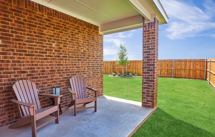 Covered patio featuring a solid brick exterior, concrete flooring, and a large grassy yard