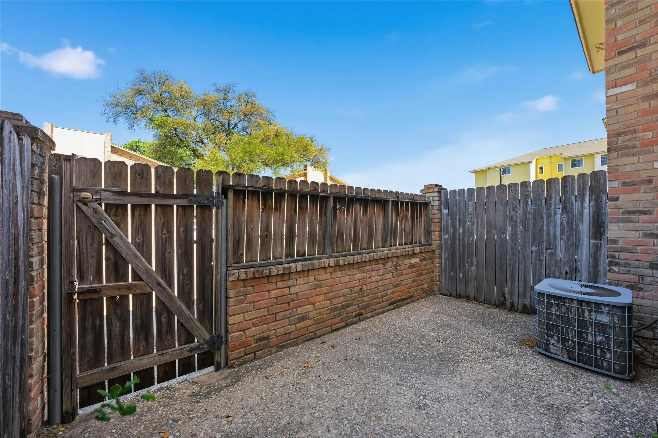 Private patio area featuring a concrete surface, wood fencing, and brick wall elements