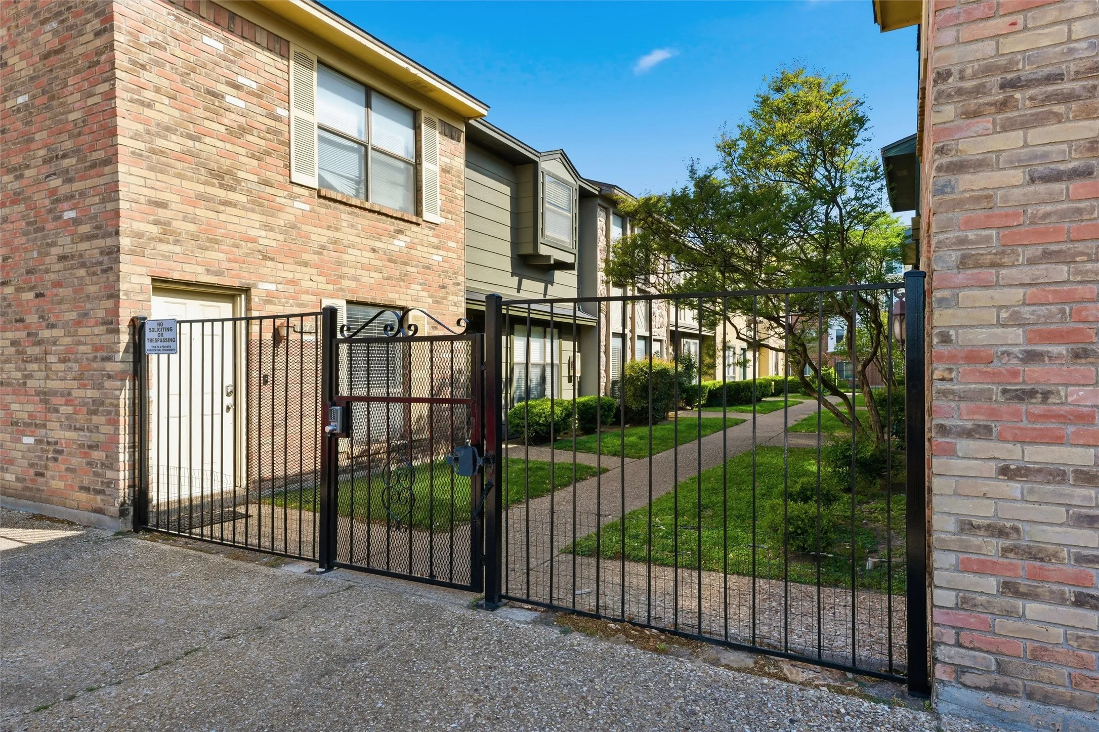 Gated entry with ornamental ironwork leading to a paved walkway