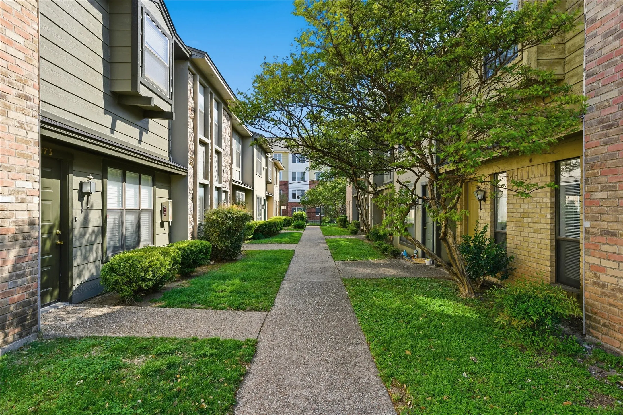 Landscaped walkway with mature trees and lush green lawns