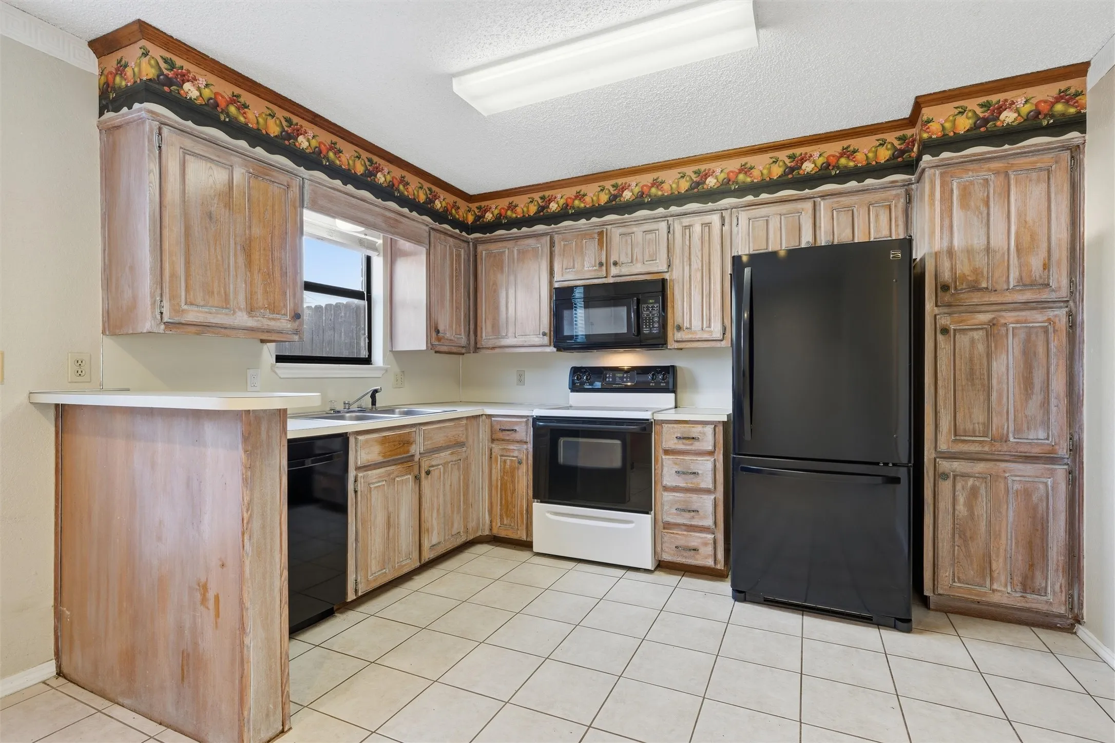 Kitchen featuring wood-finish cabinetry, white countertops, a built-in microwave, and tile flooring