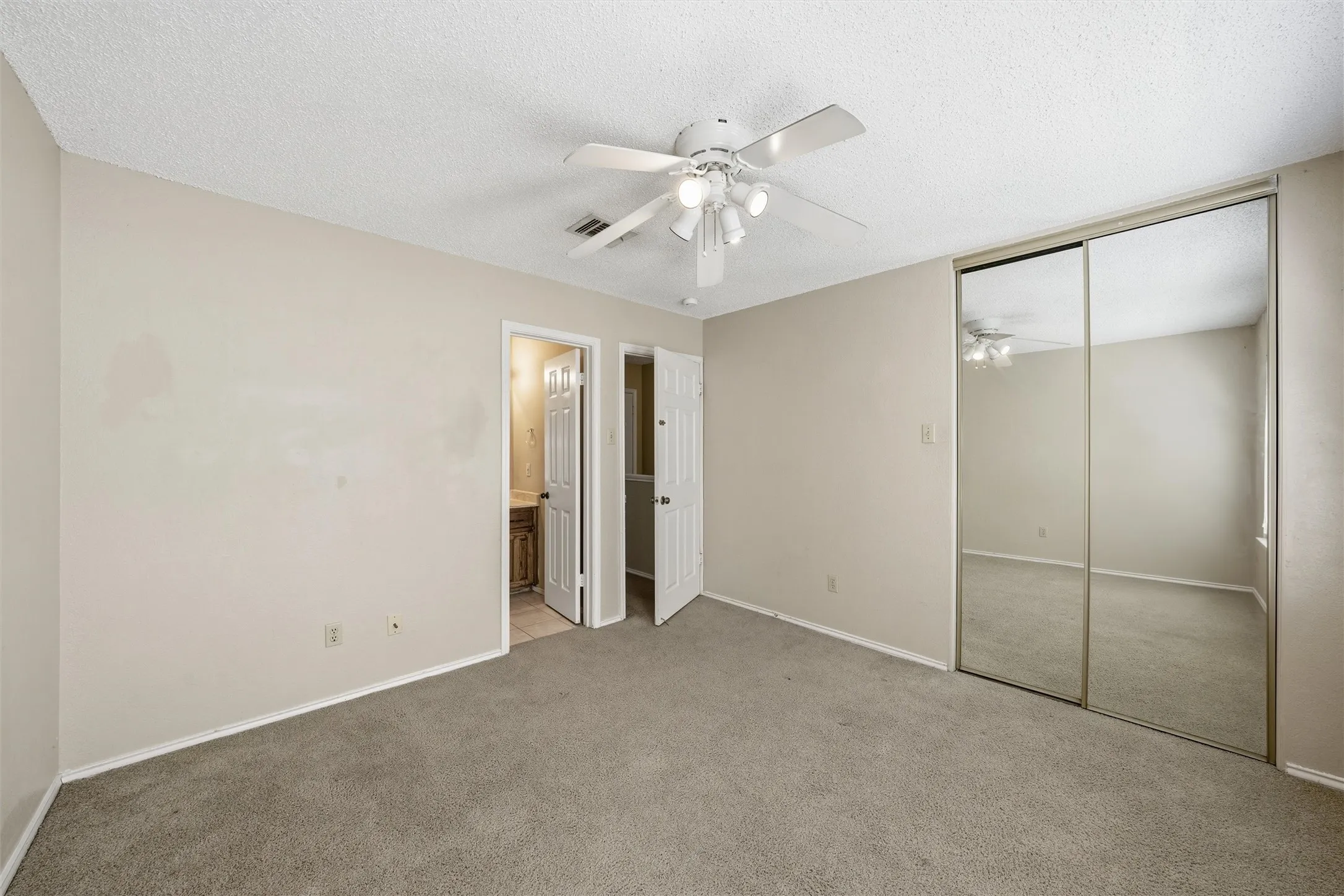 Carpeted flooring, ceiling fan with integrated lighting, mirrored closet doors, and neutral wall tones