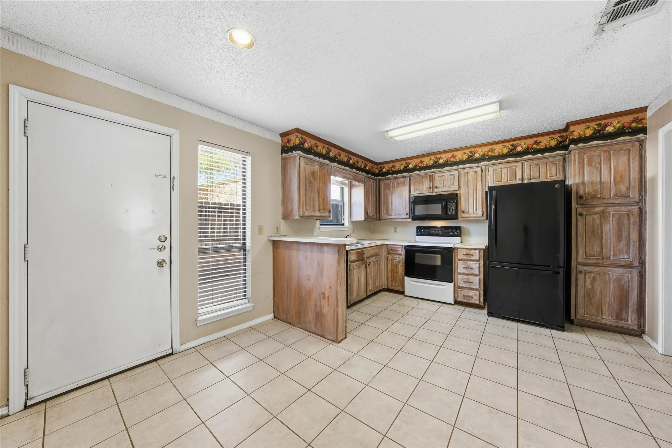 Kitchen featuring wood-finish cabinetry, tile flooring, and integrated black appliances