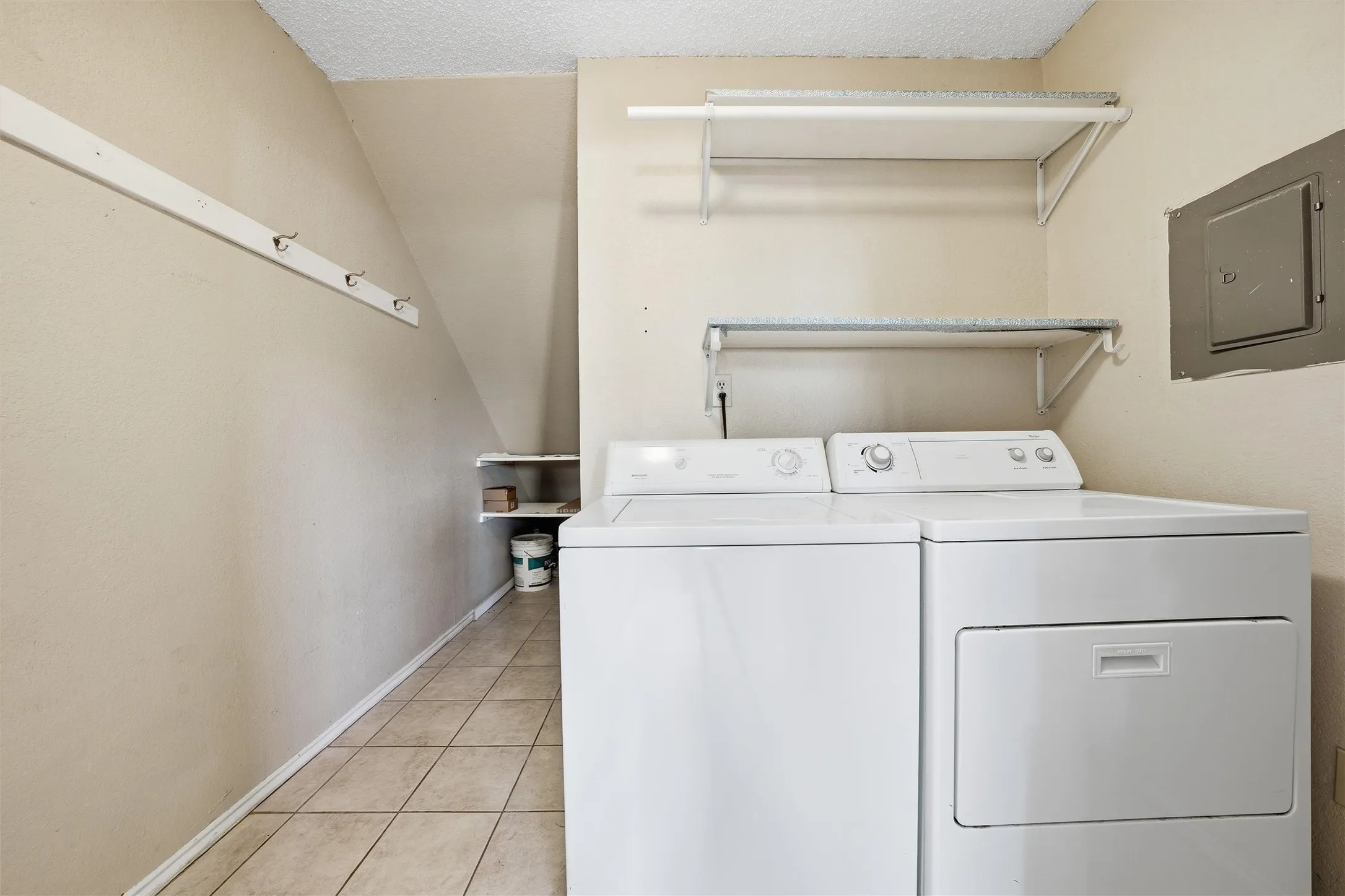 Tiled flooring laundry area with built-in shelving and wall-mounted drying rack