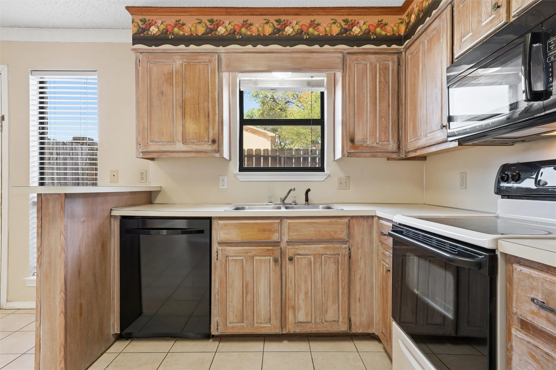 Kitchen featuring wood-finish cabinetry, black appliances, a double basin sink, and tile flooring