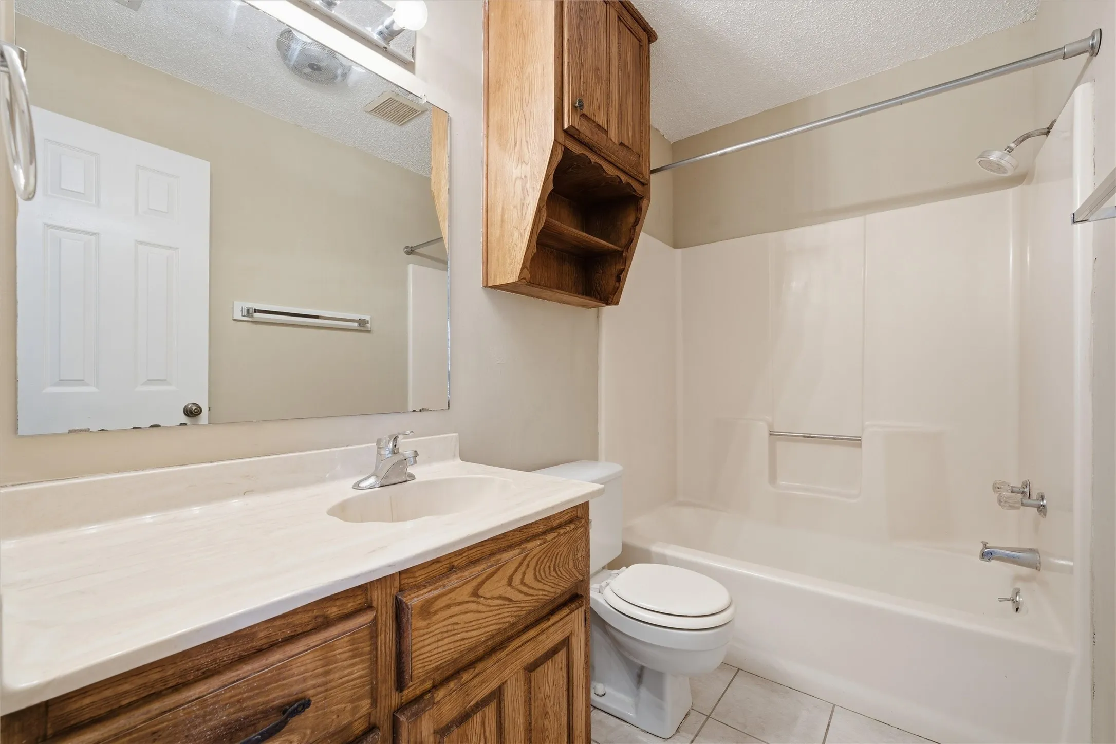 Vanity with wood-finish cabinetry, light-toned countertop, and integrated sink