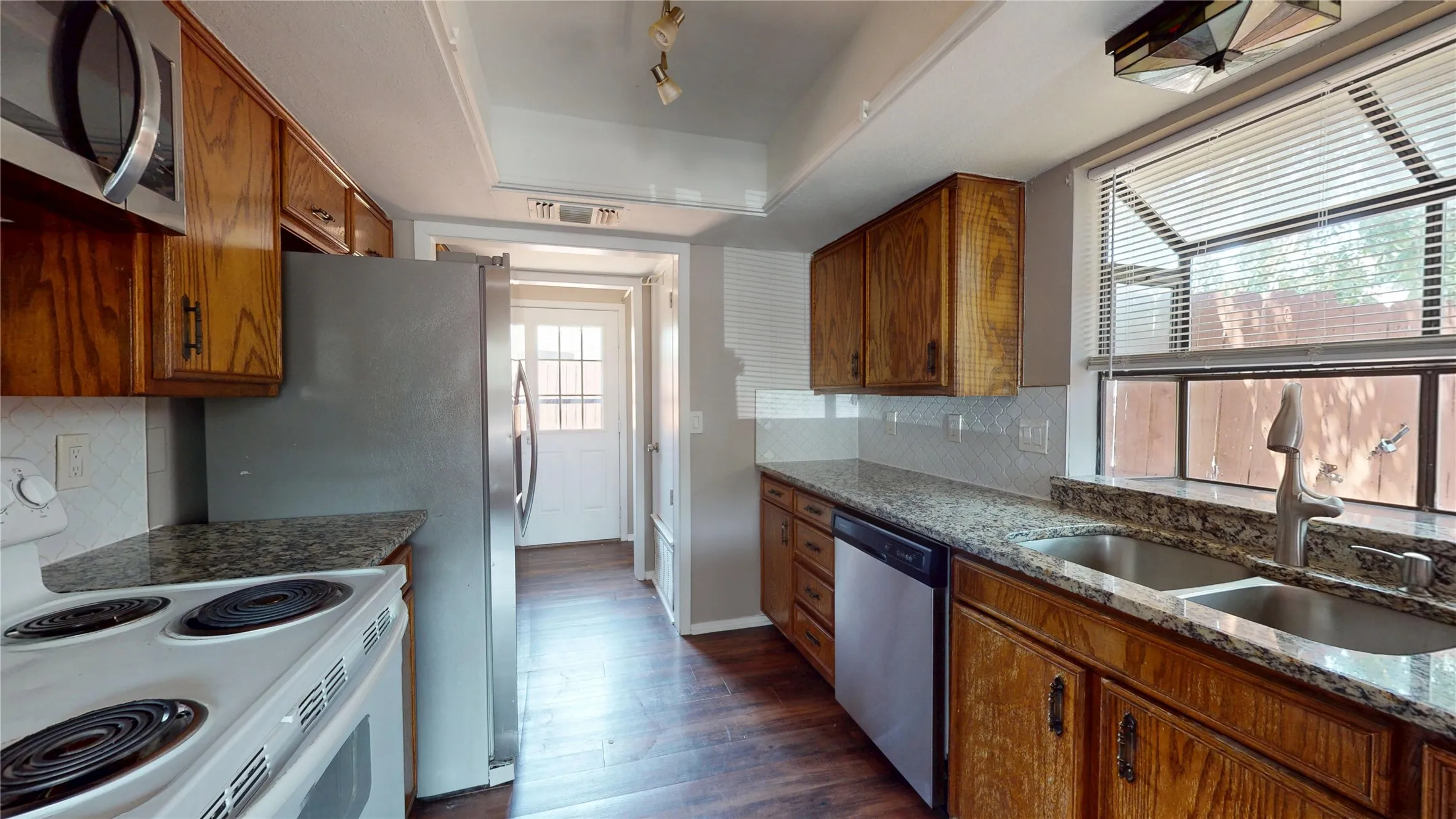 Kitchen featuring wood-finish cabinetry, stone-finish countertops, and a dual basin sink