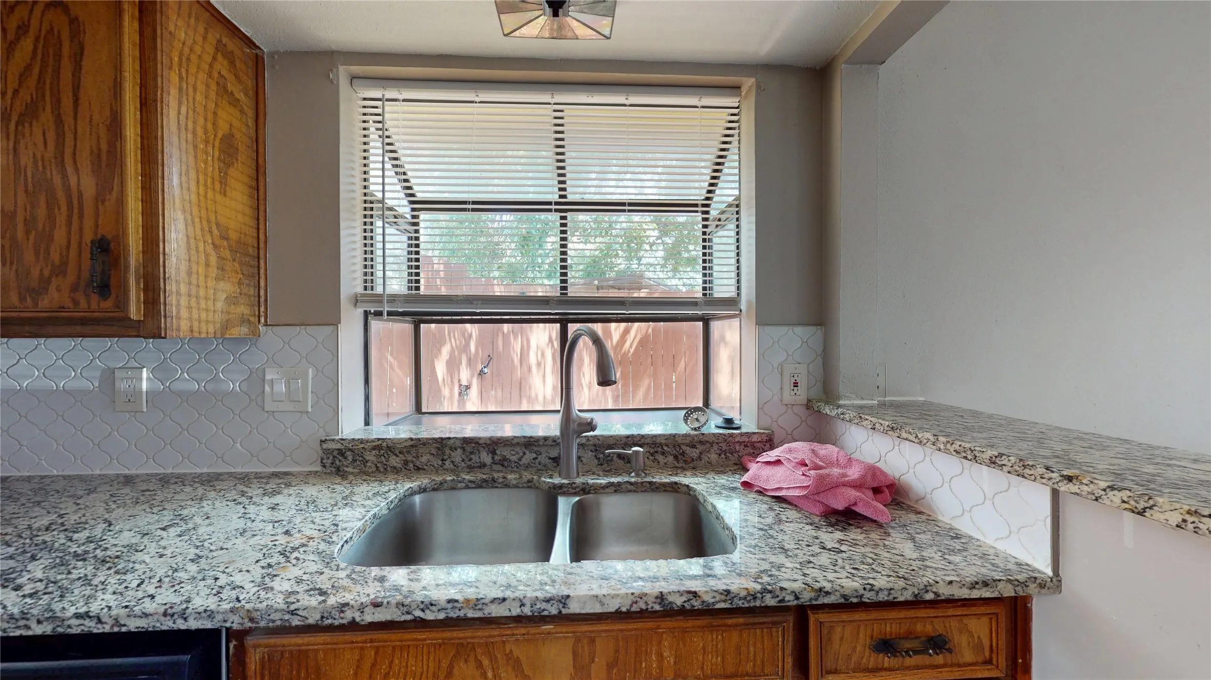 Granite-style countertops with an undermount stainless steel sink, a high-arc faucet, and a patterned tile backsplash