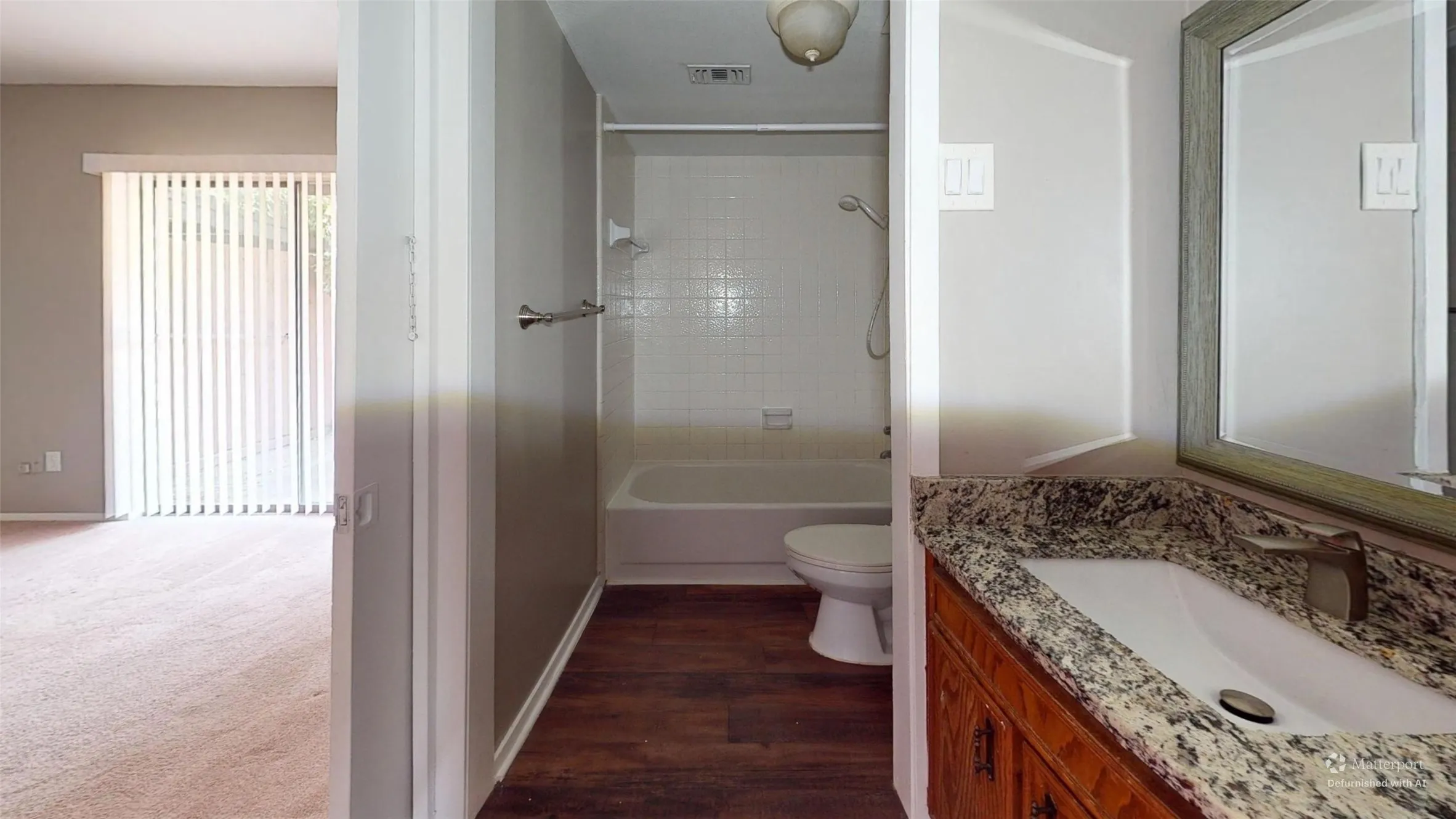 Bathroom featuring a vanity with a granite-style countertop, undermount sink, and wood-finish cabinetry